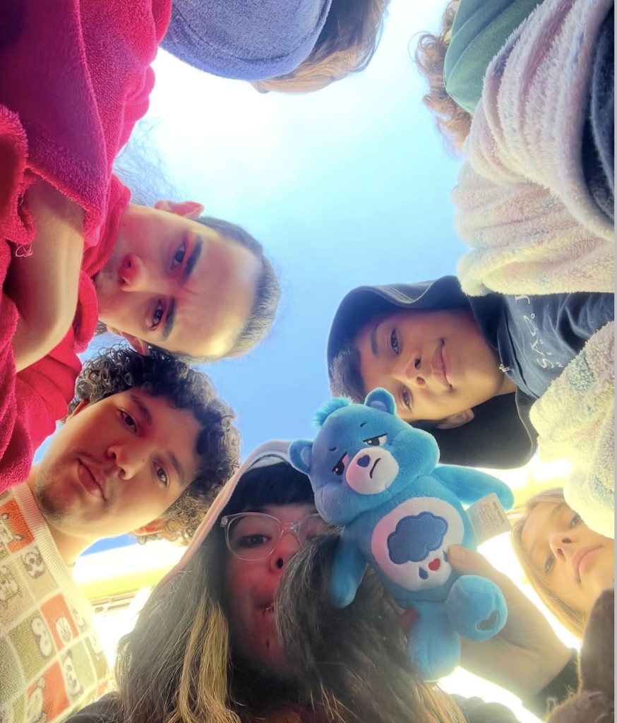 Gabi e os amigos em círculo, com um ursinho azul