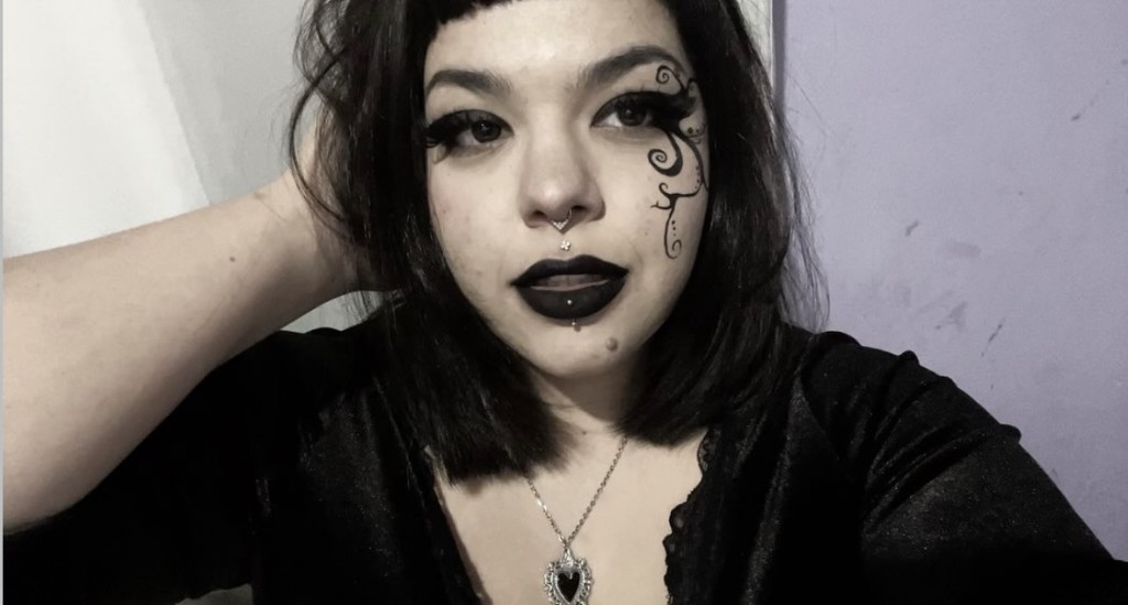 Gabi aos 20 anos, maquiagem preta, colar de coração