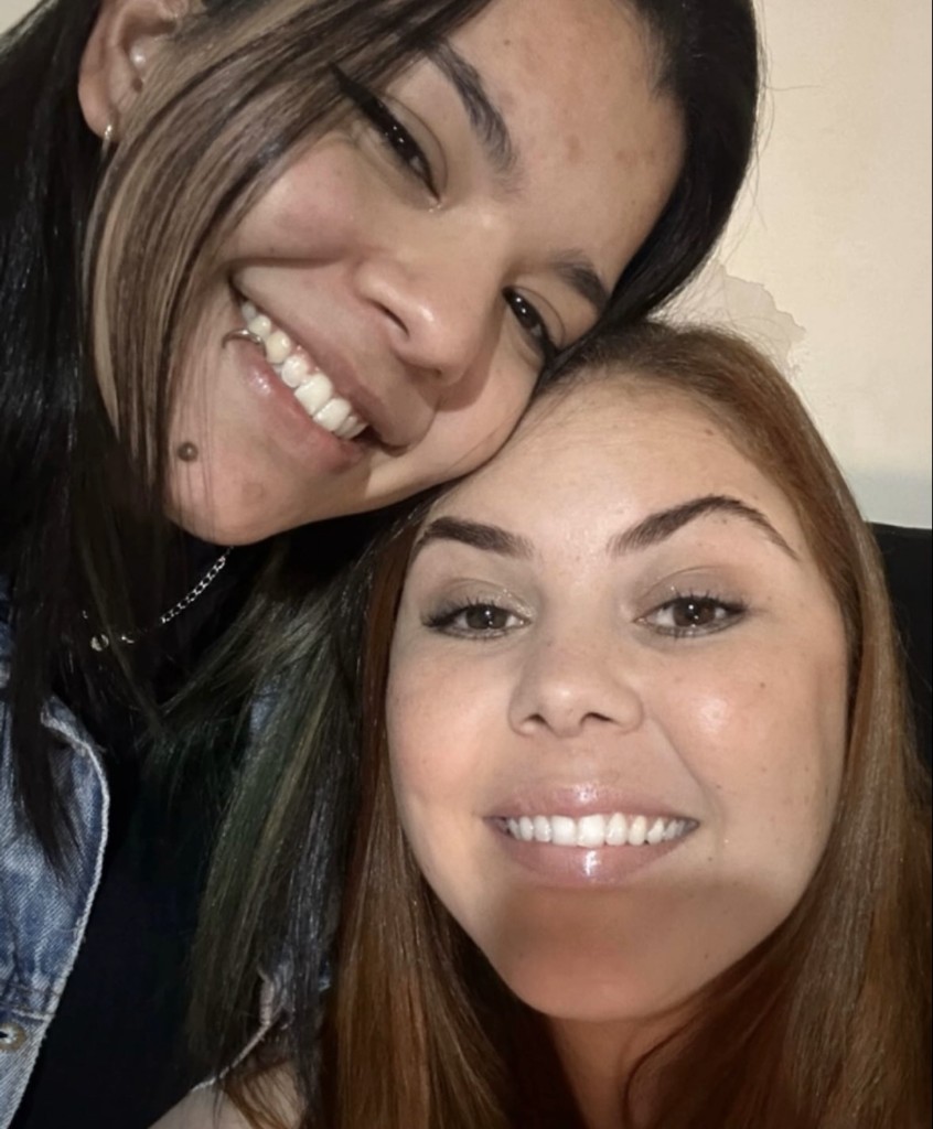 Gabi de cabelo preto em cima e a Pudimzinha de cabelo mais claro embaixo, sorrindo juntas